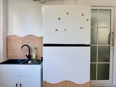a kitchen with white cabinets and a refrigerator at Nana Best Hostel in Makkasan
