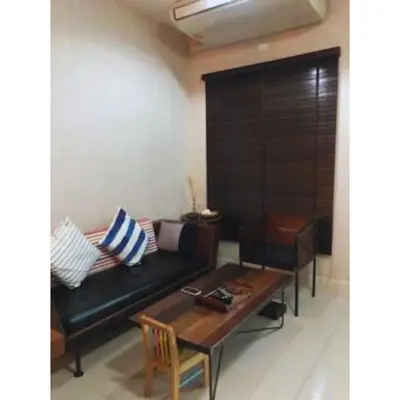 a living room with a black couch and a table at Leon Sukhumvit 62 in Bangkok