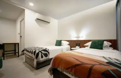 a hotel room with two beds with green pillows at Palma Hotel in Bangkok