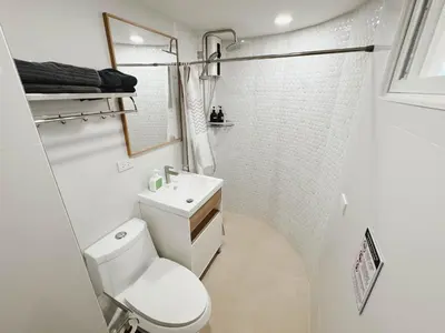 a white bathroom with a toilet and a shower at Silom Hideaway 27 Floor City View, 4-min to BTS in Bangkok