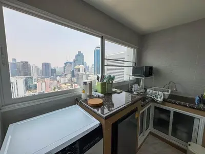 a kitchen with a view of a city from a window at Silom Hideaway 27 Floor City View, 4-min to BTS in Bangkok