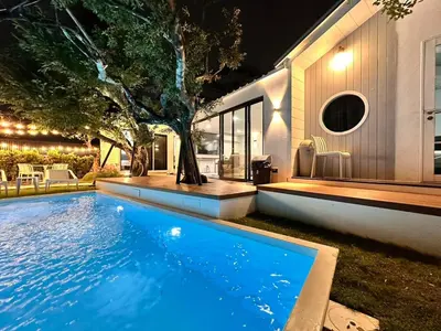 a swimming pool in front of a house at night at The Lodge Bangkok Poolvilla 2 in Sathani Khlong Tan