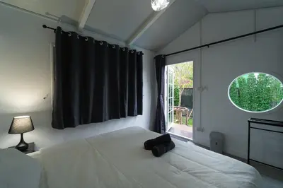 a bedroom with a white bed and a window at The Lodge Bangkok Poolvilla 2 in Sathani Khlong Tan