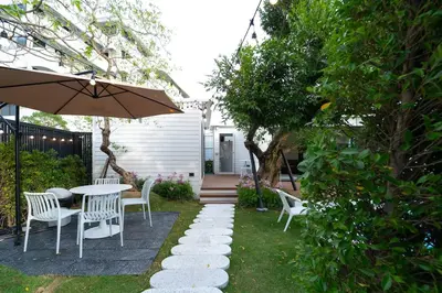 a patio with a table and chairs and an umbrella at The Lodge Bangkok Poolvilla 2 in Sathani Khlong Tan