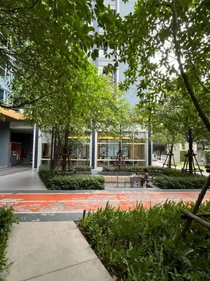 a park with benches and trees in front of a building at Lumpini Park Vibhavadi-Chatuchak in Bangkok
