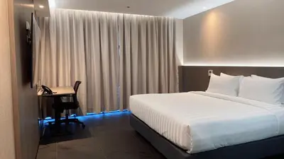 a bedroom with a bed and a desk and a window at Bangkok City Rama 9 Hotel in Bangkok