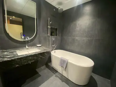 a bathroom with a tub and a sink and a mirror at Bangkok City Rama 9 Hotel in Bangkok