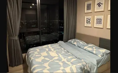 a bed in a room with a view of a city at Bangna Apartment Ideo in Ban Khlong Samrong