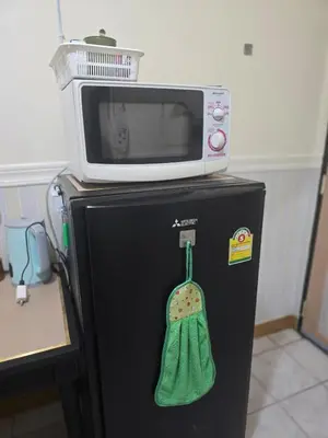 a microwave sitting on top of a black refrigerator at 114 Boutique style apartment with Air Con and free Wi-fi in Bangkok