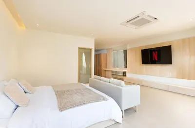 a bedroom with a white bed and a tv at Spacious 4BR Muji Home with Loft Pool in Ekkamai in Bangkok