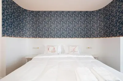 a bedroom with a white bed with a blue patterned wall at Elegant King BR Apt Bathtub, BTS Central BKK BTB8 in Bangkok
