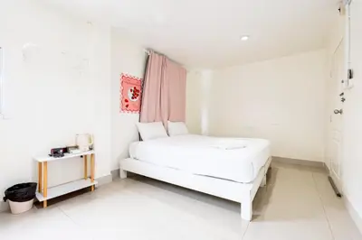 a white bedroom with a bed and a table at xx Oh My Napz Sukhumvit 3 - สุขุมวิท ซอย 3 in Makkasan