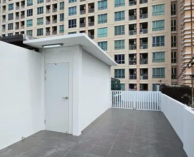 a white building with a door in front of a building at Loly Residence in Bangkok