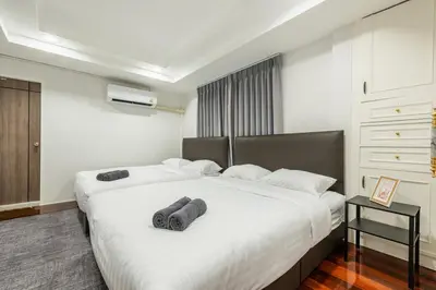 a bedroom with a large white bed with two pillows at SavasdeeVilla Midtown bangkok in Makkasan