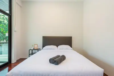 a bedroom with a large white bed with two pillows at SavasdeeVilla Midtown bangkok in Makkasan