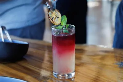 a drink sitting on a wooden table with a lemon slice at Little Tree Hut Bangkachao in Bang Chak