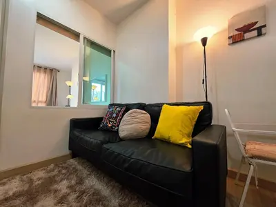 a black leather couch with yellow pillows in a living room at Super spacious city view apartment close to King Power Mahanakhon Pixel Building Silom Road Patpong Night Market 2 minutes to BTS rail transit bourgeois lifestyle neighborhood in Bangkok