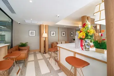 a waiting room with orange chairs and a counter with flowers at Marwin Terra Hotel in Bangkok