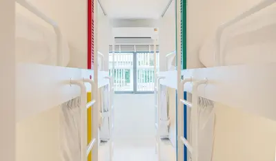 a dressing room with white shelves and a door at Bedd Hostel in Bangkok