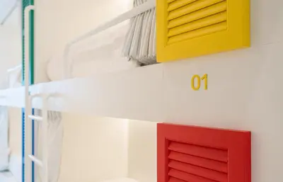 a red and yellow door on a white wall at Bedd Hostel in Bangkok