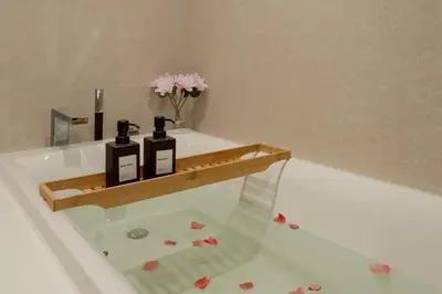 a bath tub with two bottles on a wooden shelf at 2BR2BA BTS Thonglor Rooftop Pool Gym BBQ Low in Bangkok