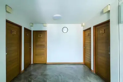 a hallway with wooden doors and a clock on a wall at XX GO INN Khaosan Bangkok - ถนนข้าวสาร กรุงเทพมหานคร Pro in Bang Bua Thong Railway Station