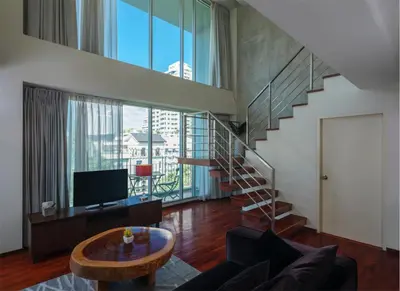 a living room with a staircase and a television at Silom Lofts in Bangkok
