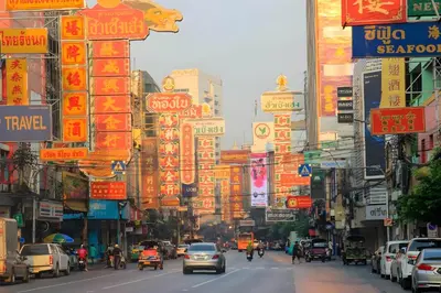 a busy city street filled with lots of traffic and signs at Mitr Inn Yaowarat Road in Samphanthawong