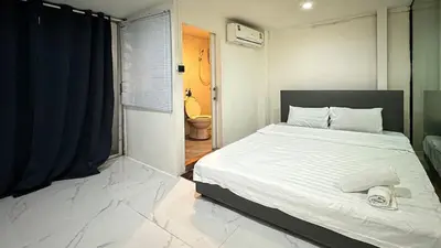 a bedroom with a large white bed and a bathroom at Chubby5room12 in Ban Bang Phlat