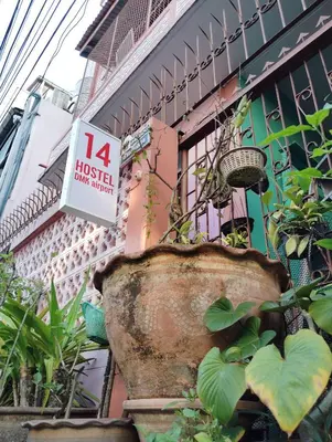 a building with a sign in front of it with plants at 14 Hostel DMK airport in Bang Khen
