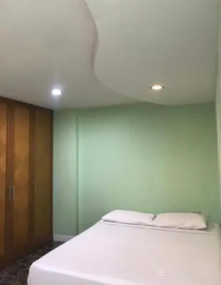 a white bed in a room with a green wall at mint apartment in Sathani Bang Su