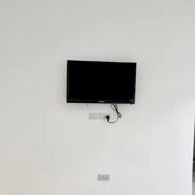 a flat screen tv hanging on a white wall at z Rest Inn Silom - เรสท์ อินน์ สีลม in Bang Rak