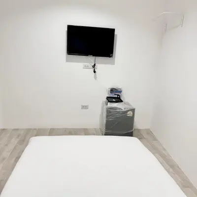 a white room with a bed and a flat screen tv at XX Rest Inn Silom Bangkok in Bang Rak
