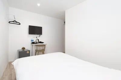 a bedroom with a white bed and a desk at XX Rest Inn Silom Bangkok in Bang Rak