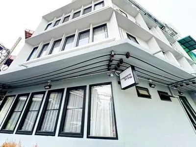 a white building with a sign in front of it at Common Living Bangkok in Bangkok