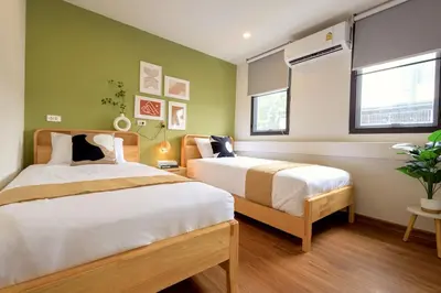 two beds in a bedroom with green walls at Common Living Bangkok in Bangkok