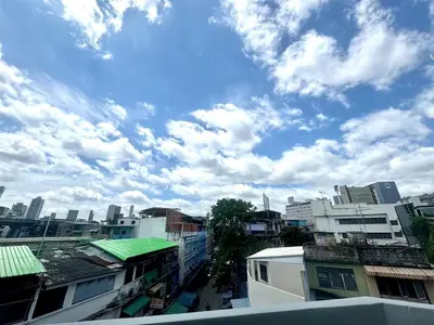 a city street with buildings and a cloudy sky at Common Living Bangkok in Bangkok