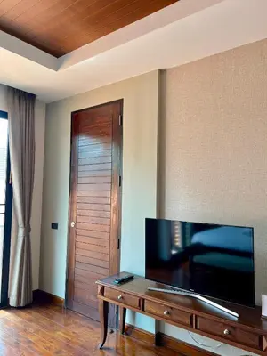 a living room with a television and a wooden door at Yotaka Bangkok Hotel in Bangkok