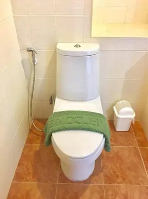 a bathroom with a toilet with a green towel on it at Grandview Ladprao Hotel in Bangkok