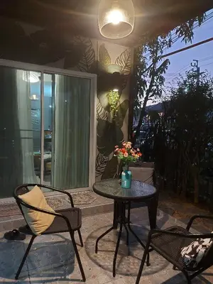 a patio table with two chairs and a vase with flowers on it at Cosy Preuksa House 120 in Bang Yai