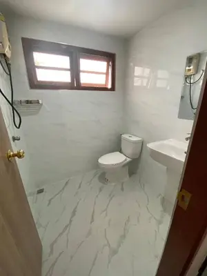 a white bathroom with a toilet and a sink at Beautiful 2 story newly renovated bungalow house in Amphoe Phra Khanong