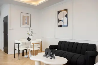 a living room with a black couch and tables at Luxe apartments in Pratunam