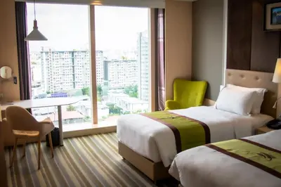 a hotel room with two beds and a desk and a window at The Bazaar Hotel Bangkok - MRT Lat Phrao Ratchadapisek in Bangkok