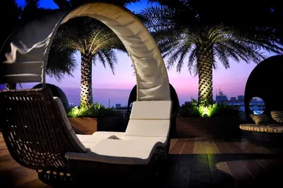 a swinging chair on a rooftop with palm trees at The Bazaar Hotel Bangkok - MRT Lat Phrao Ratchadapisek in Bangkok