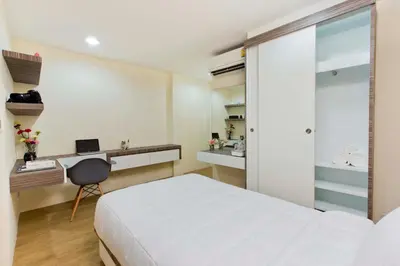 a bedroom with a bed and a desk with a laptop at Thanabhumi in Bangkok