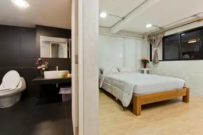a bedroom with a bed and a sink and a toilet at Thanabhumi in Bangkok