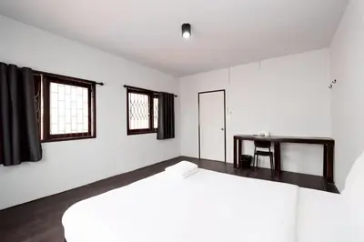 a white bedroom with a large bed and windows at xx Mitr Inn Khaosan - มิตร อินน์ ข้าวสาร in Bangkok