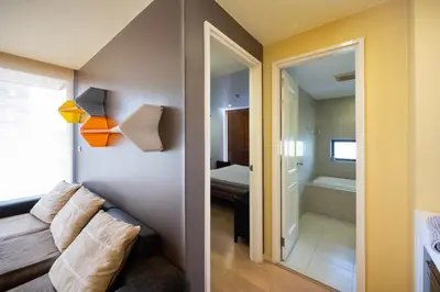 a living room with a couch and a bathroom at Beautiful 1 bed with huge Lumpini park view in Bangkok