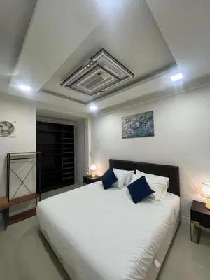 a bedroom with a large white bed with blue pillows at Huai Khwang Townhome in Ban Na Song