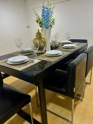 a black dining room table with glasses and a vase of flowers at Huai Khwang Townhome in Ban Na Song